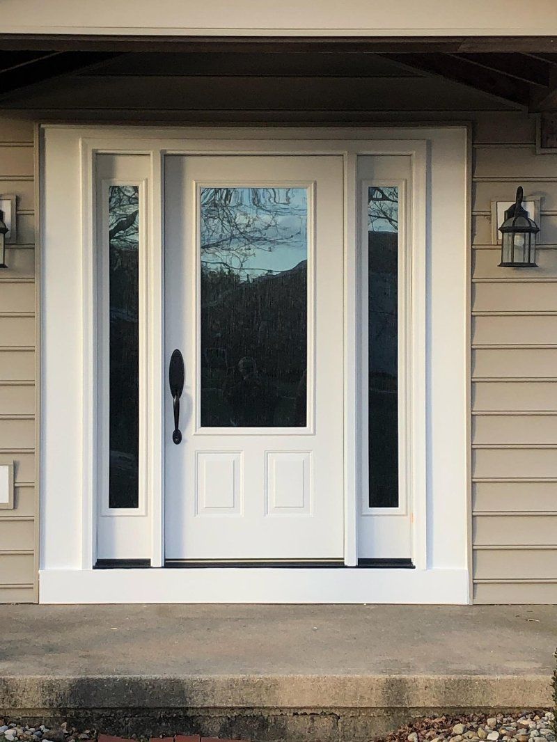 A white front door with a lot of windows on a house.