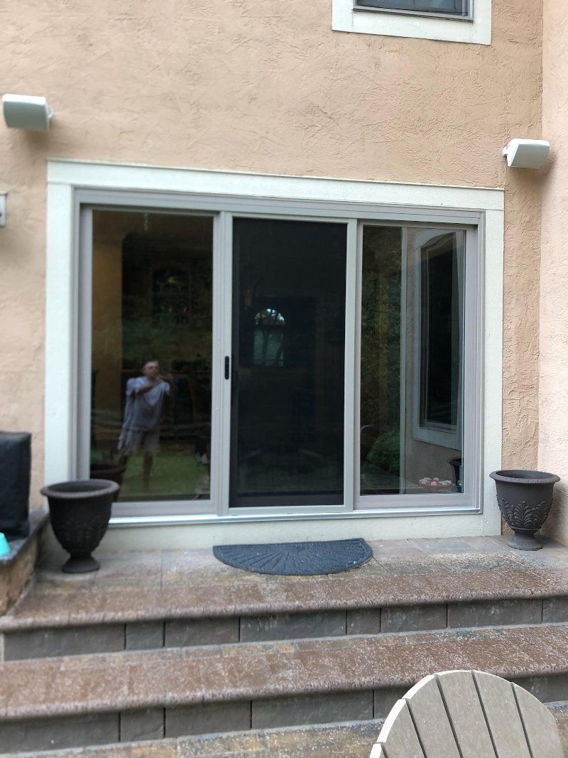 A man is standing in front of a sliding glass door.