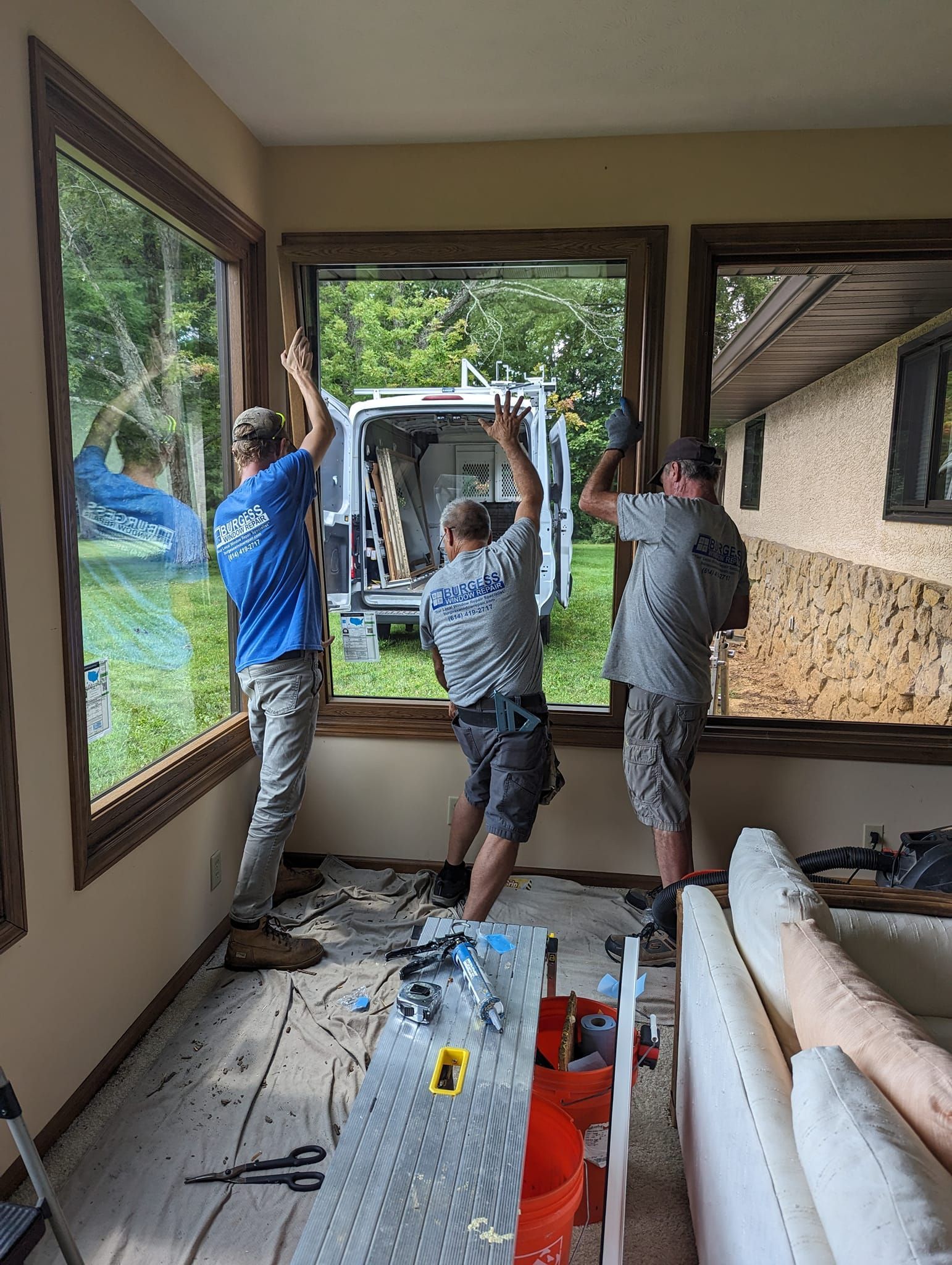 A group of men are installing a window in a living room.