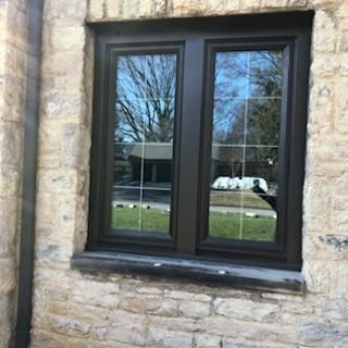 A window on the side of a stone building with a black frame.