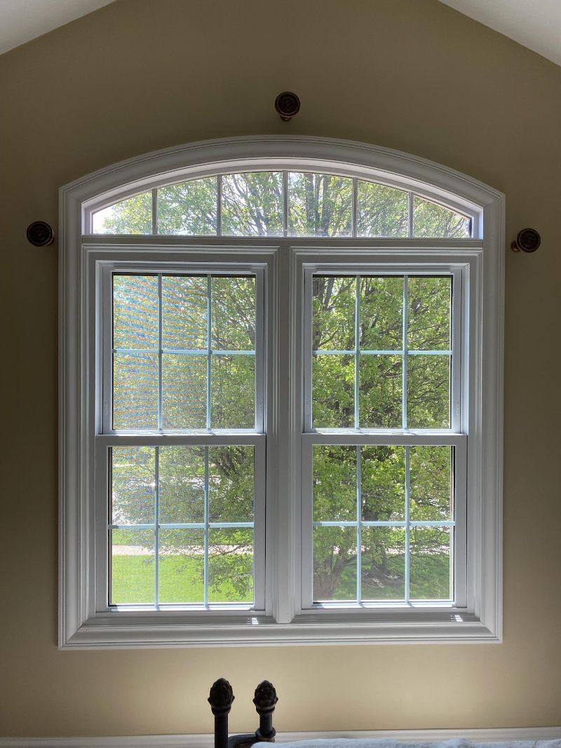 A large window with a view of trees and a sink in front of it.