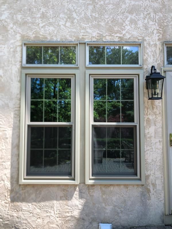 Two windows are on the side of a building next to a door.