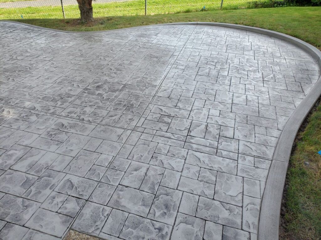 Stamped concrete patio with a curved edge and a block pattern.
