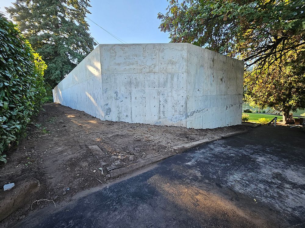 Concrete structure against trees and dirt. Asphalt path in the foreground.