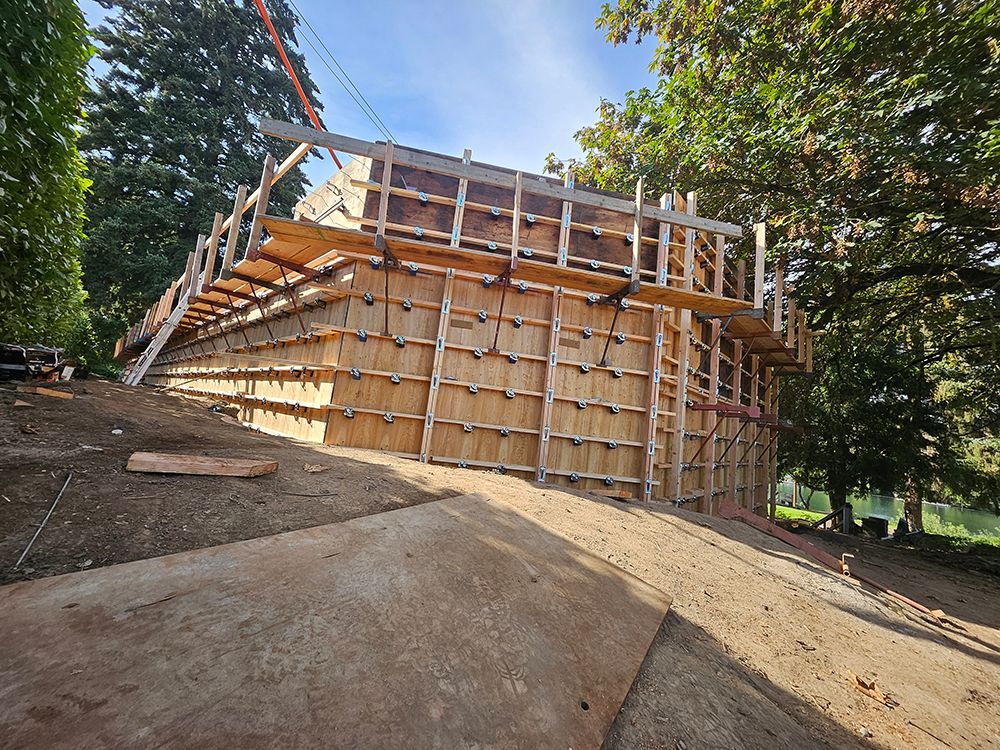 Construction site: Wooden forms on a hillside, possibly for a retaining wall or foundation.