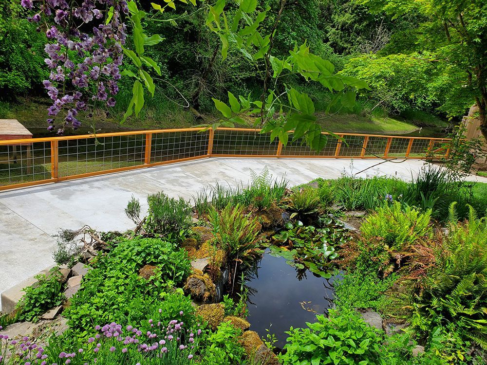 A lush garden with a pond and a decorative bridge with a wooden handrail.