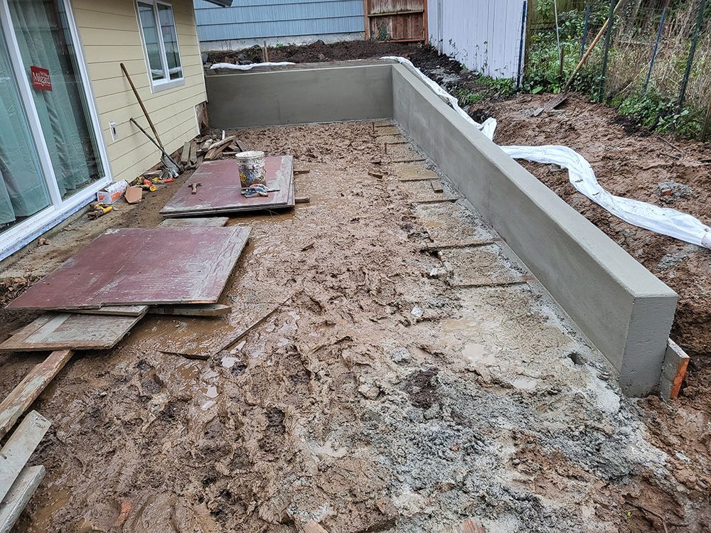 Construction site with fresh concrete retaining wall and exposed dirt.