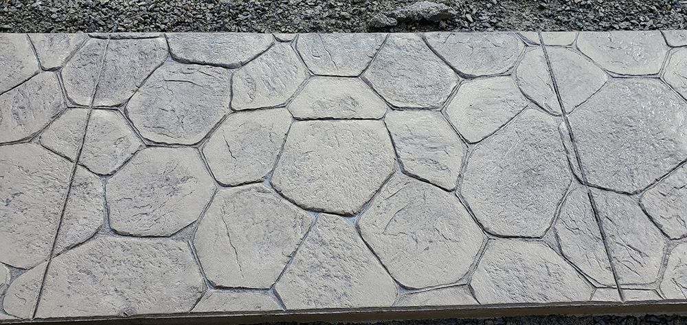 Gray concrete pavement with textured, rounded stone pattern.