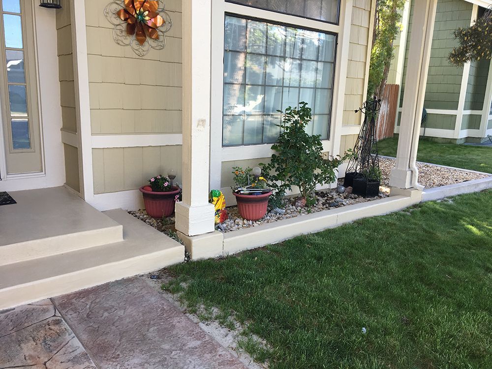 Exterior of house with plants in pots and a small garden bed along the front.