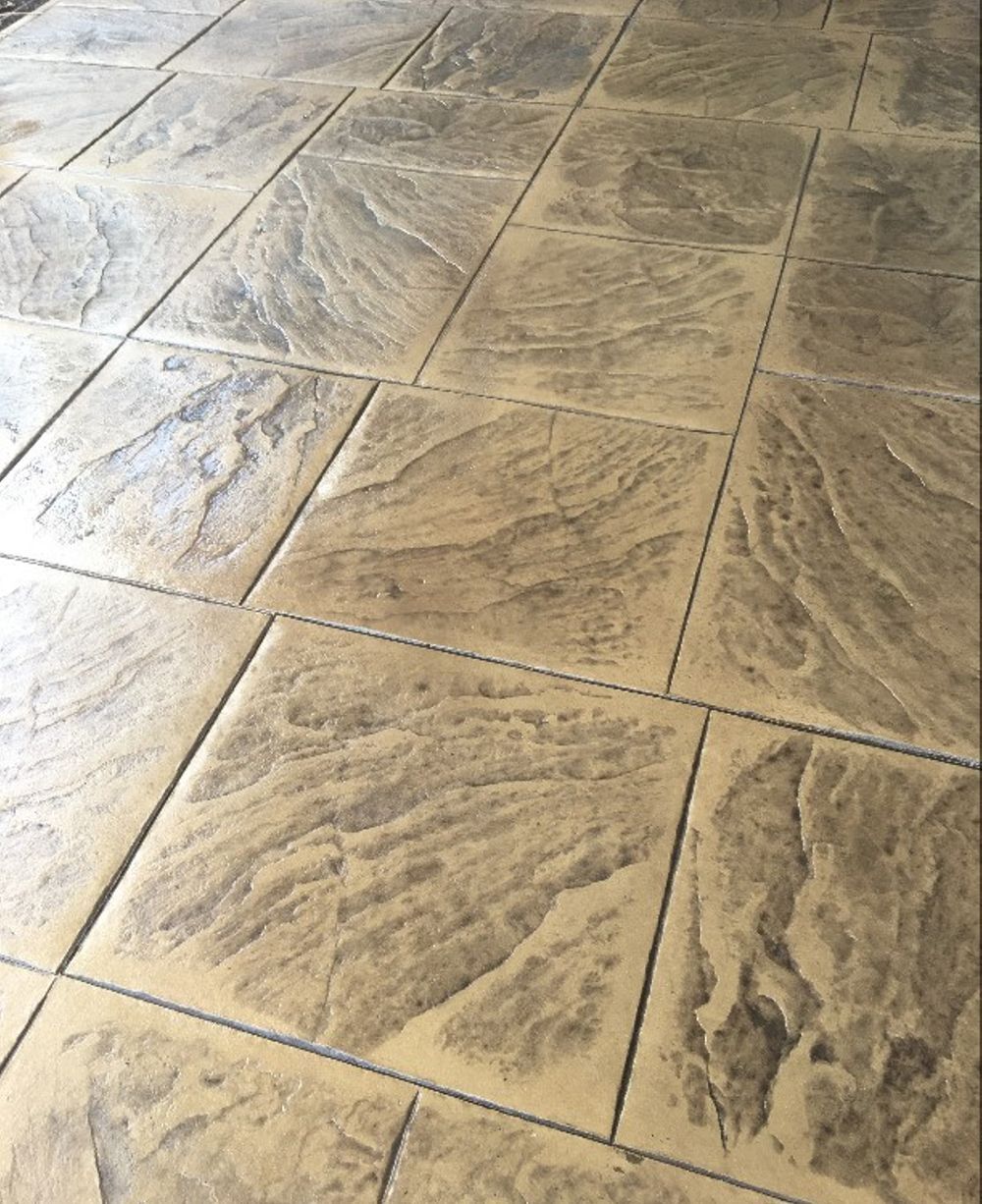 Stamped concrete patio with a flagstone design and tan coloring.