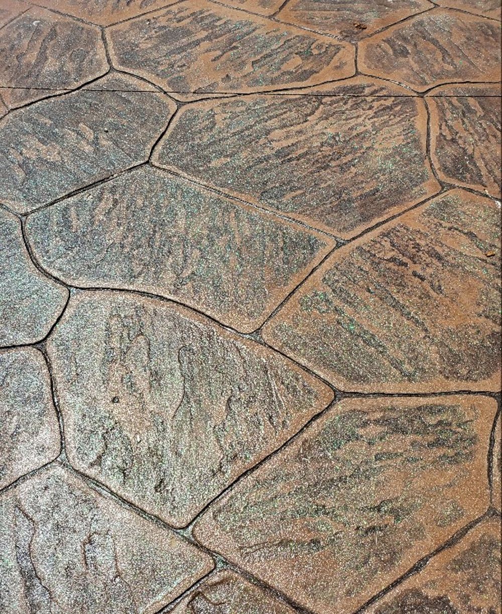 Close-up view of stamped concrete paving with an irregular stone pattern in shades of gray and brown.