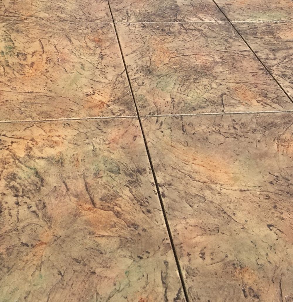 Textured, mottled concrete with a blend of earth tones and linear joints.