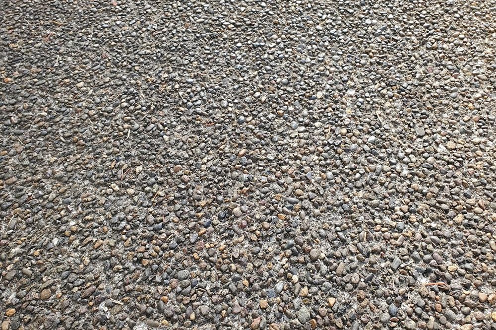 Close-up of a gravel surface. Small, rounded gray stones fill the frame, creating a textured ground.