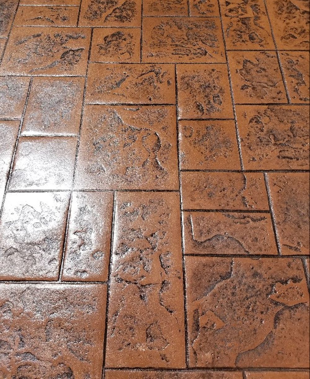 Brown and black patterned concrete flooring, resembling brick or stone pavers.