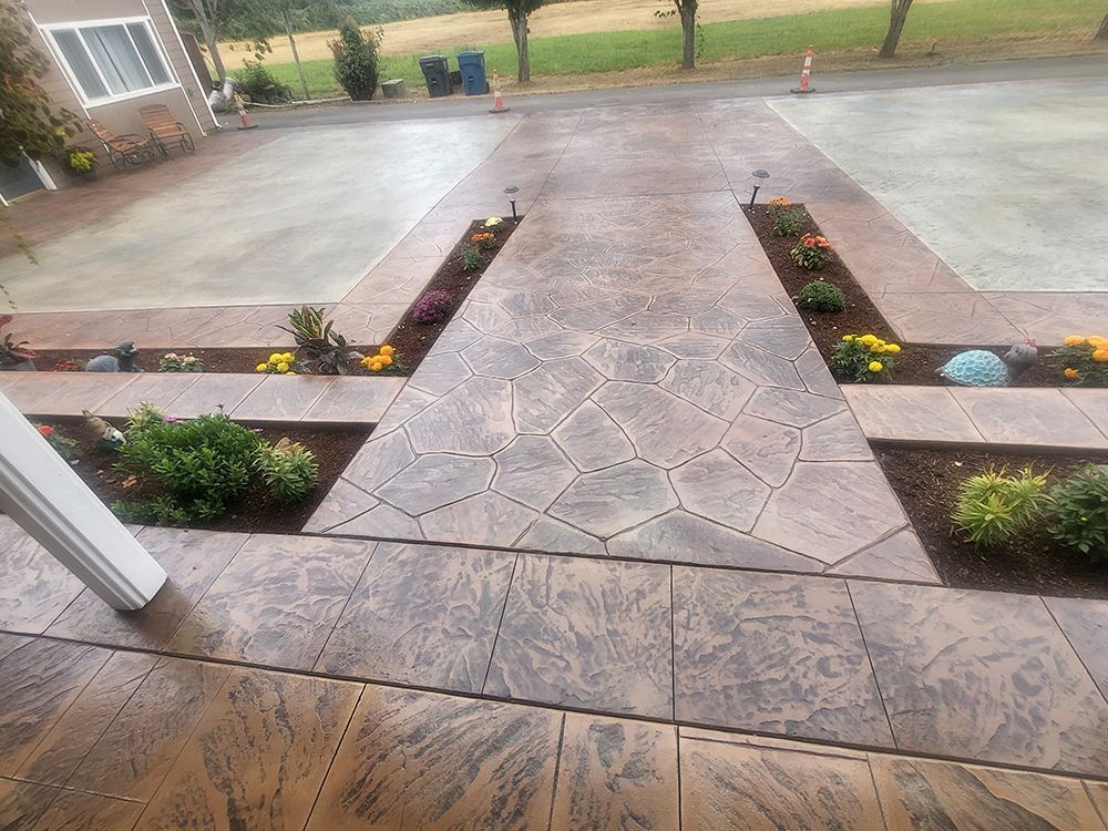 Stamped concrete driveway with flower beds and pathway.
