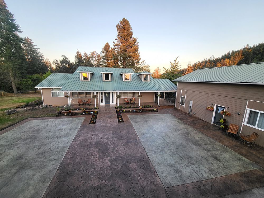 Tan house with green roof and a concrete driveway.