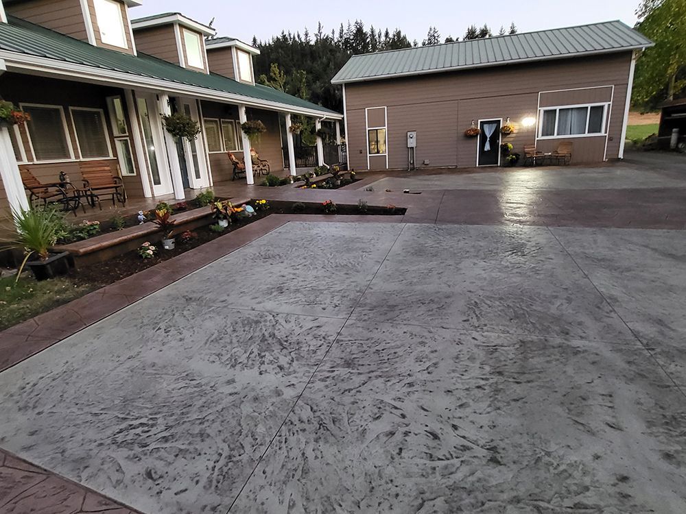Exterior view of buildings with stamped concrete driveway, flower beds, and a covered porch.