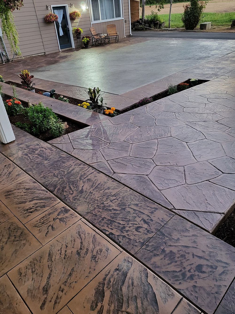 Stamped concrete steps and walkway leading to a house, with flower beds.