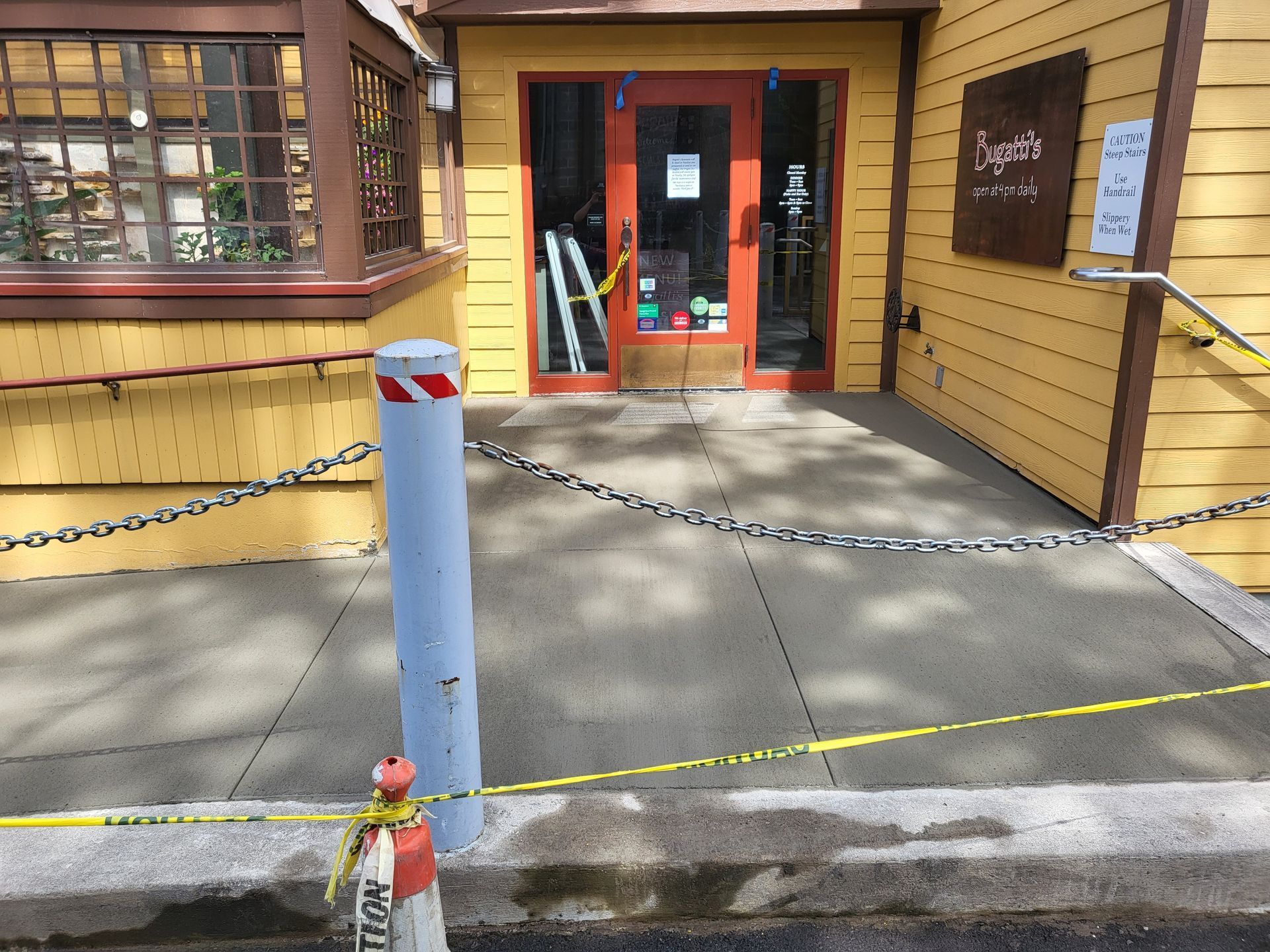 Exterior of a restaurant with a ramp, entrance blocked by caution tape and construction materials.