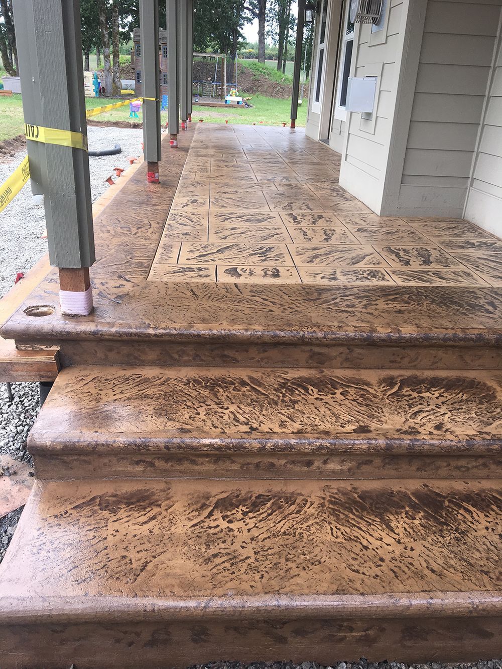 Stamped concrete porch with steps; tan and brown colors.