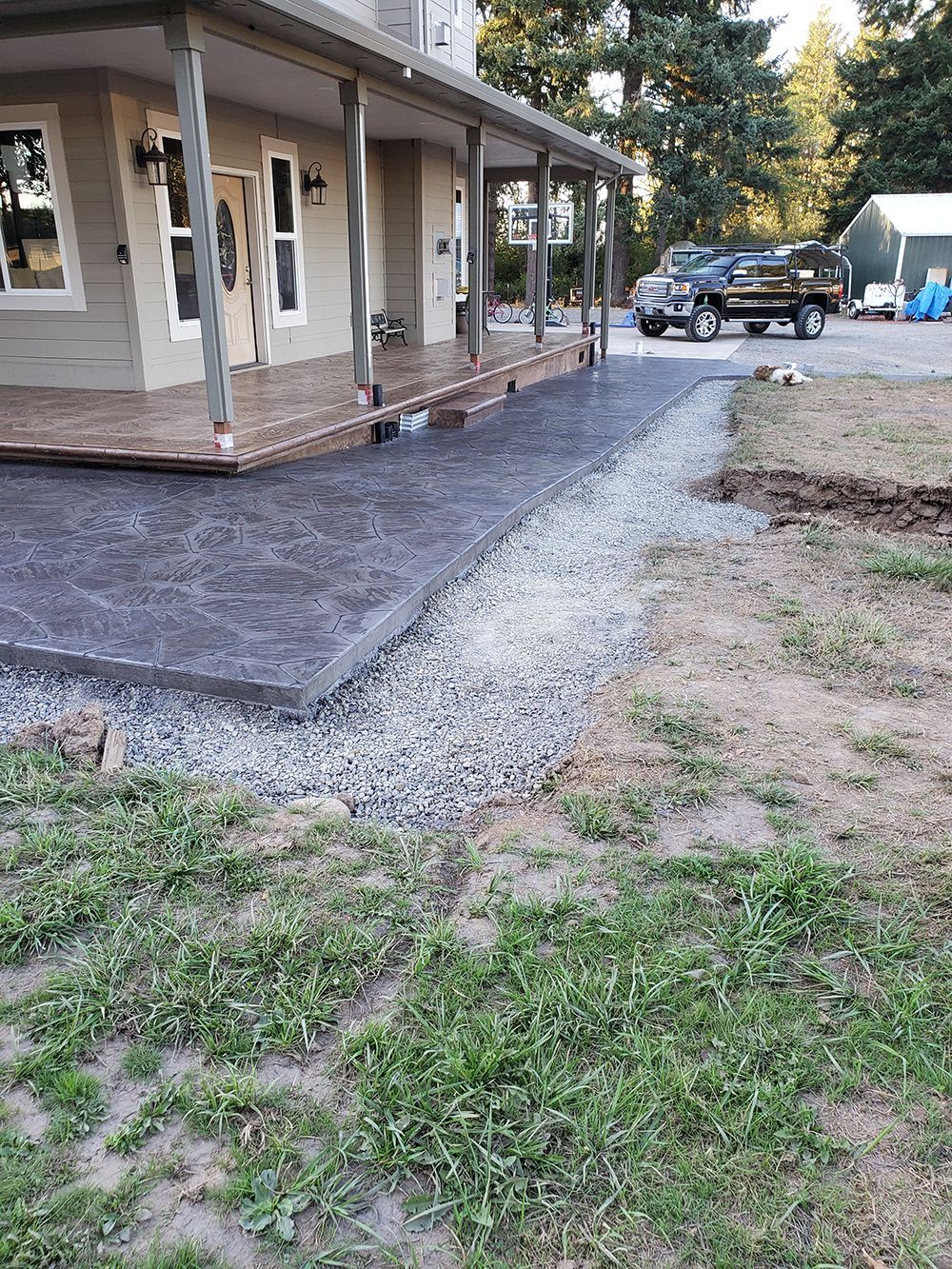 Front of house with a gray concrete walkway, gravel border, and a pickup truck parked.