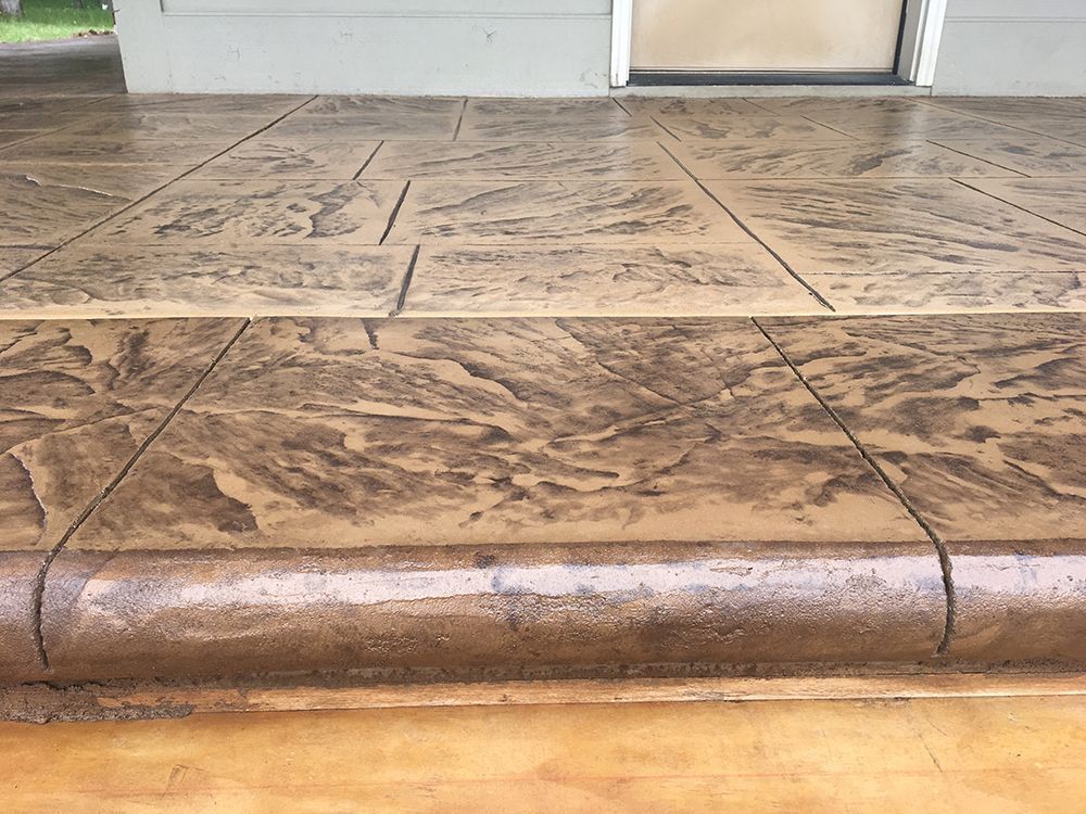 Stamped concrete porch and steps in shades of brown with a textured pattern.