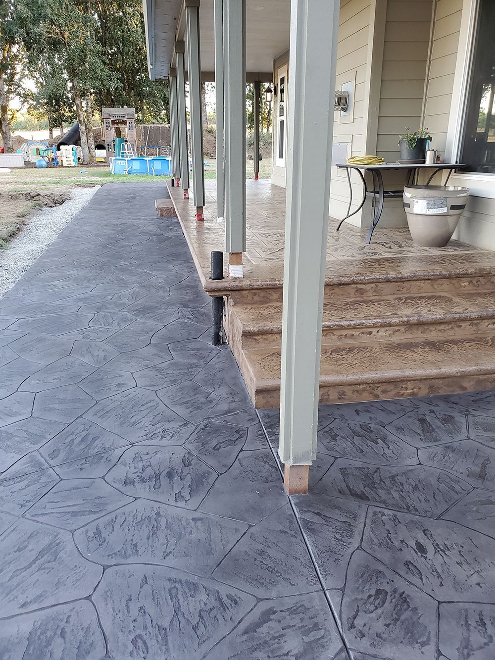 Stamped concrete walkway and porch steps with support columns.