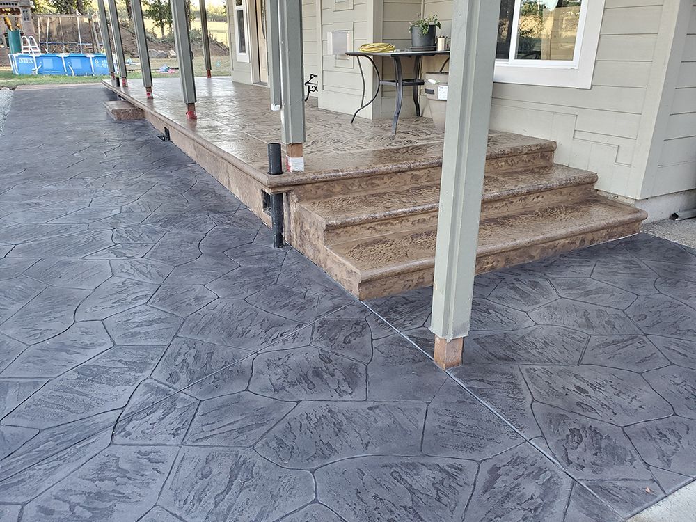 Stamped concrete patio and steps, gray and brown, leading to a house with columns.
