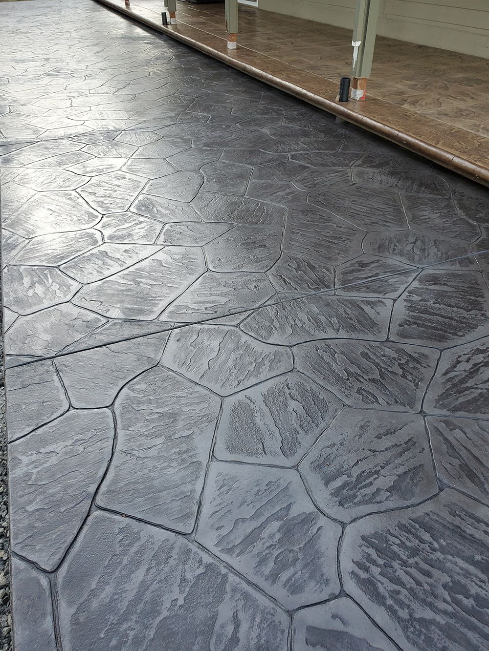 Stamped concrete pathway with dark gray, stone-like pattern.