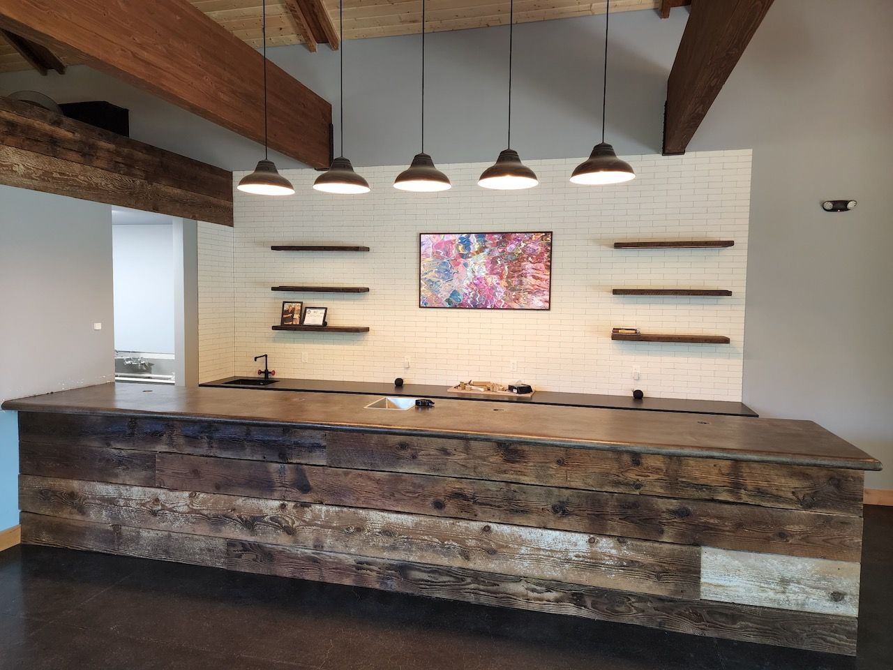 Rustic kitchen island with brick backsplash, shelves, and pendant lights.