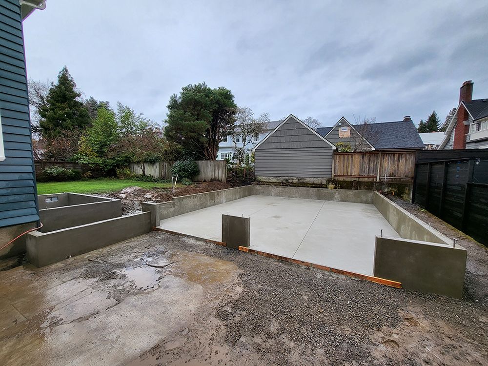 Concrete foundation and retaining walls on a residential construction site; overcast sky.