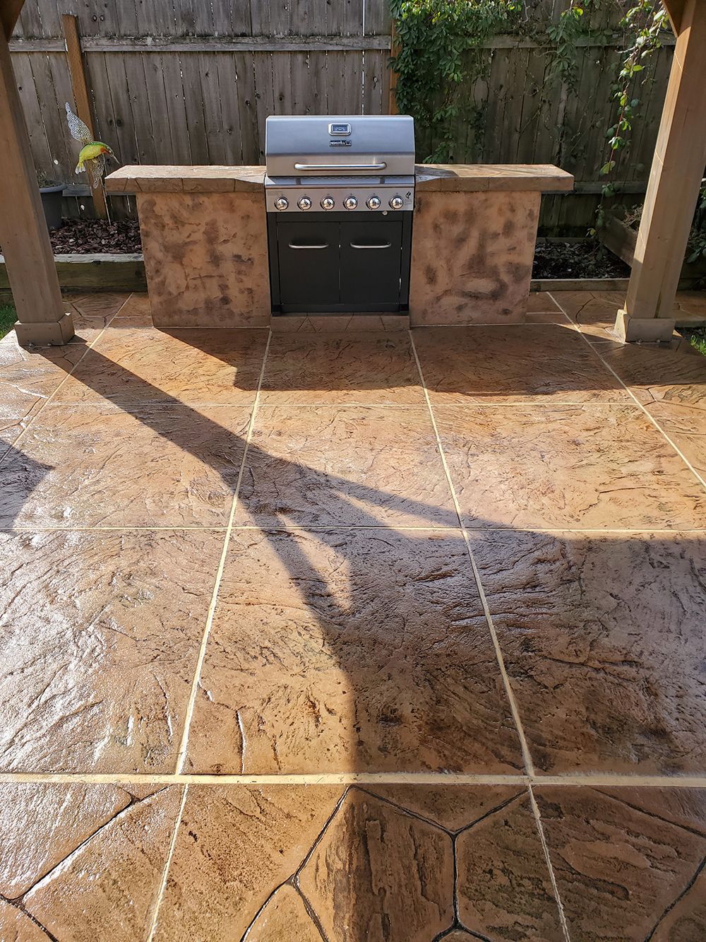 Outdoor grilling station with brown stamped concrete patio.