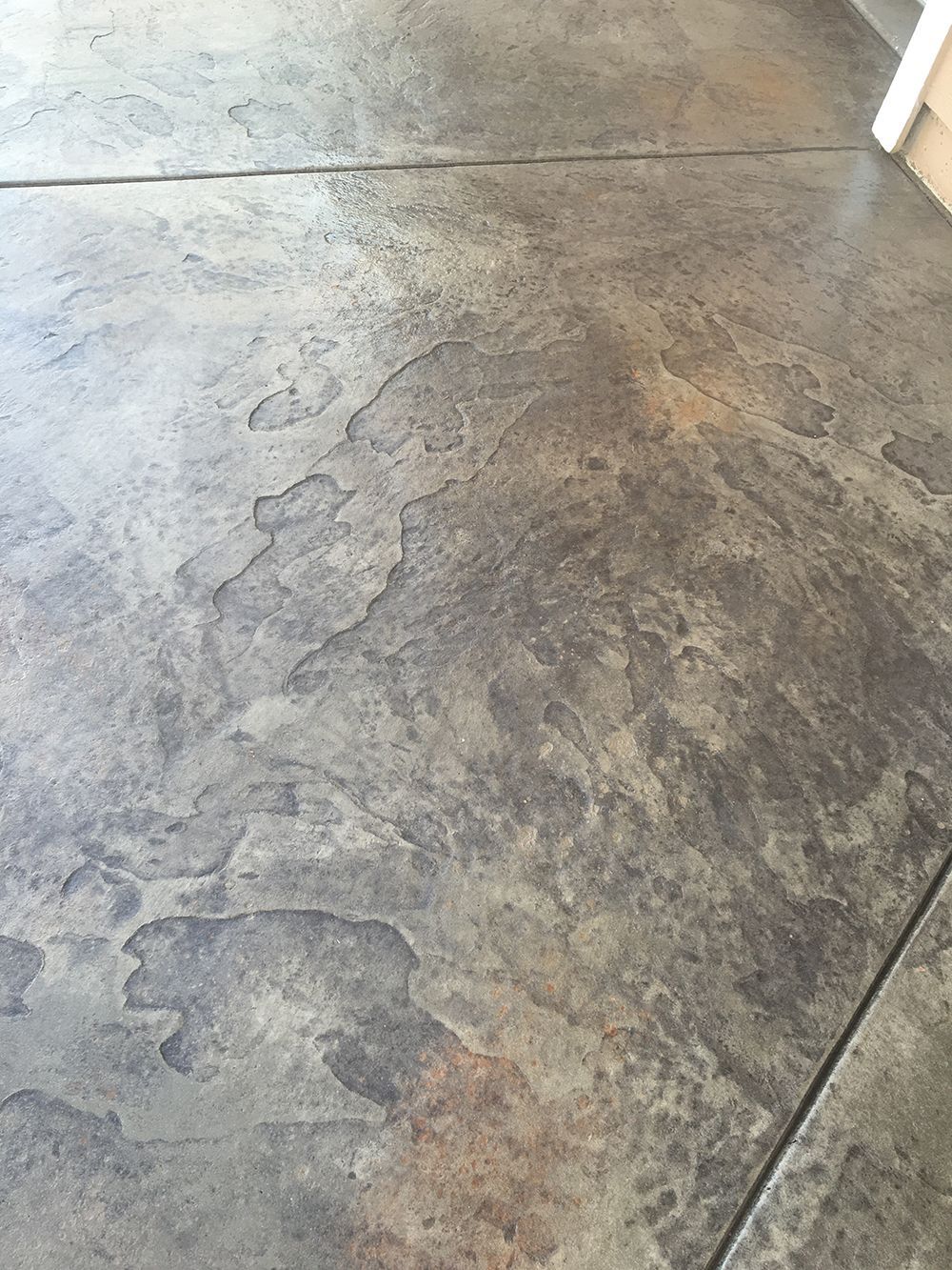 Textured concrete flooring with gray and brown tones, possibly stamped with a flagstone pattern.