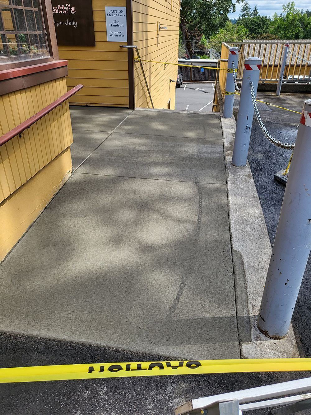 Concrete ramp leading to a building's entrance. Yellow tape across the bottom, metal railings.