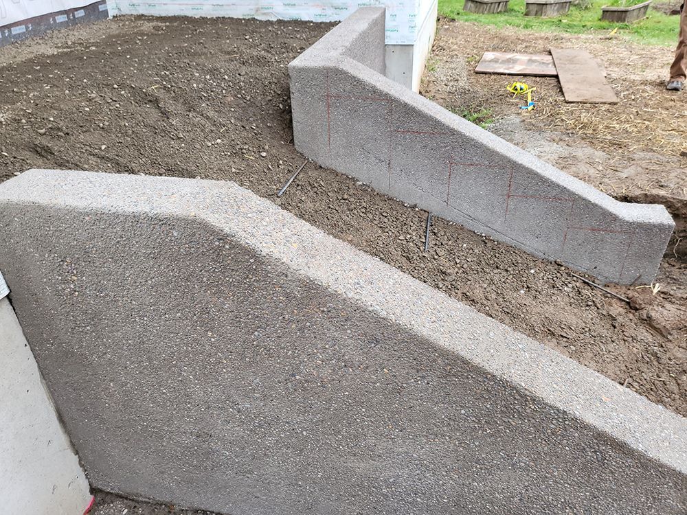 Concrete retaining walls in construction, against a sloped dirt background.