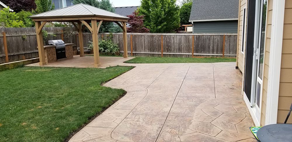 Backyard with gazebo, grill, patio, grass, and wooden fence.