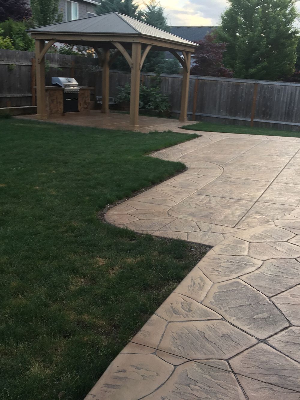 Backyard patio with stamped concrete, a gazebo with a built-in grill, and a green lawn.