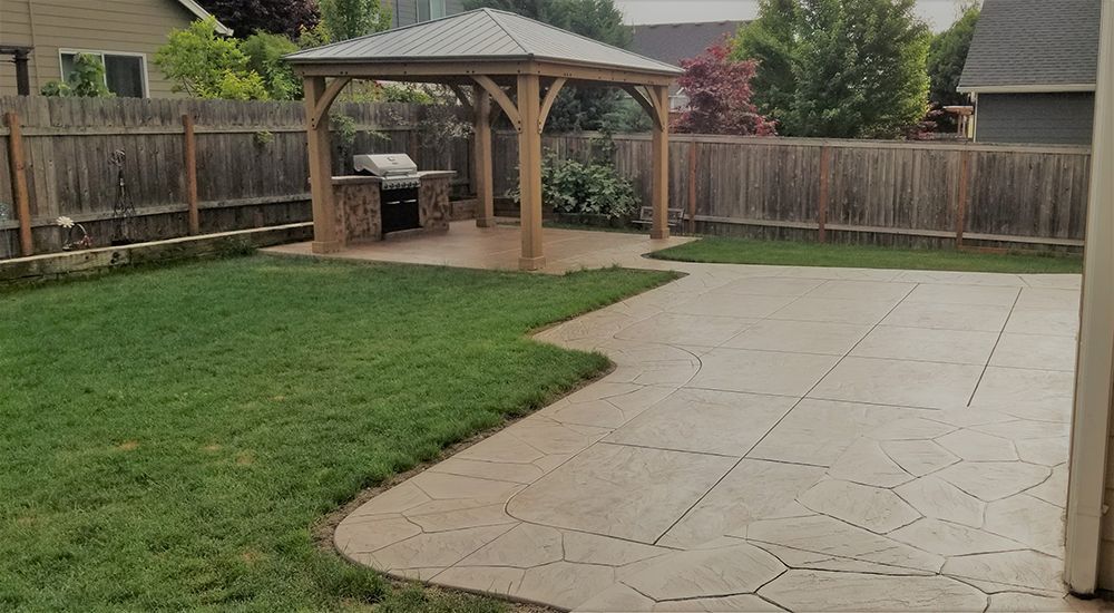 Backyard with gazebo, grill, patio, lawn, and wooden fence.