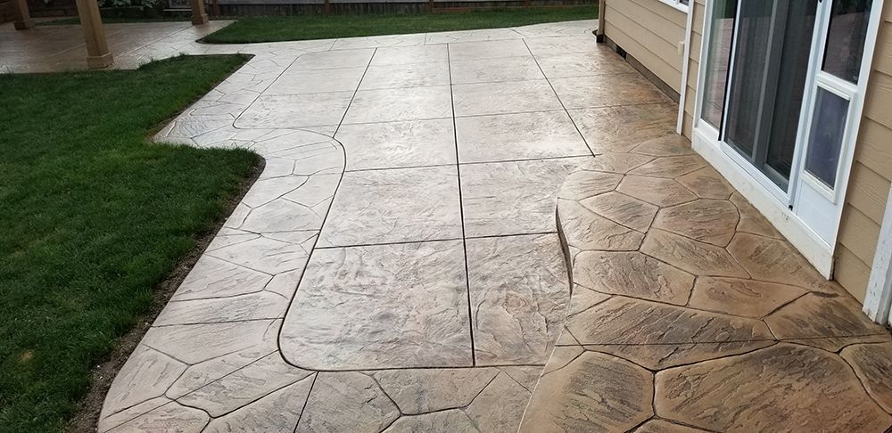Stamped concrete patio next to a house and grass.
