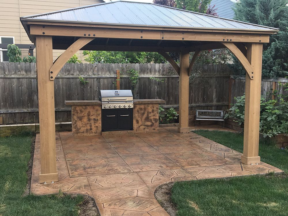 Gazebo with outdoor kitchen, grill, and seating on stamped concrete patio.