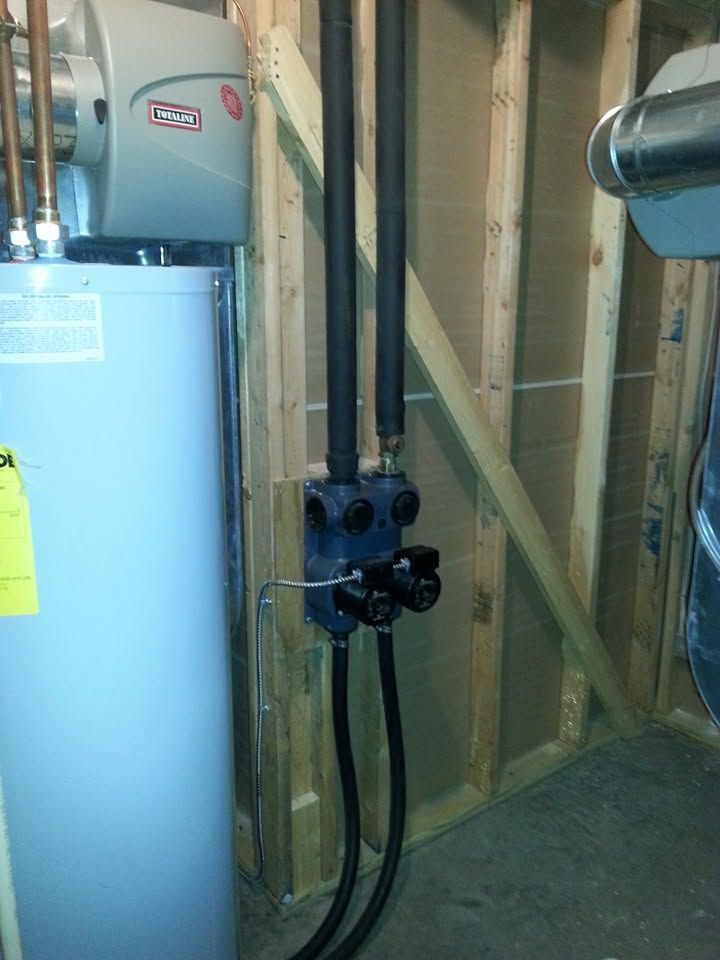 Utility room with water heater, exposed pipes, and electrical boxes on unfinished wall