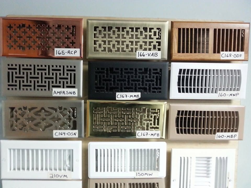 Assorted decorative metal vent grilles and air register covers displayed in a grid on a wall