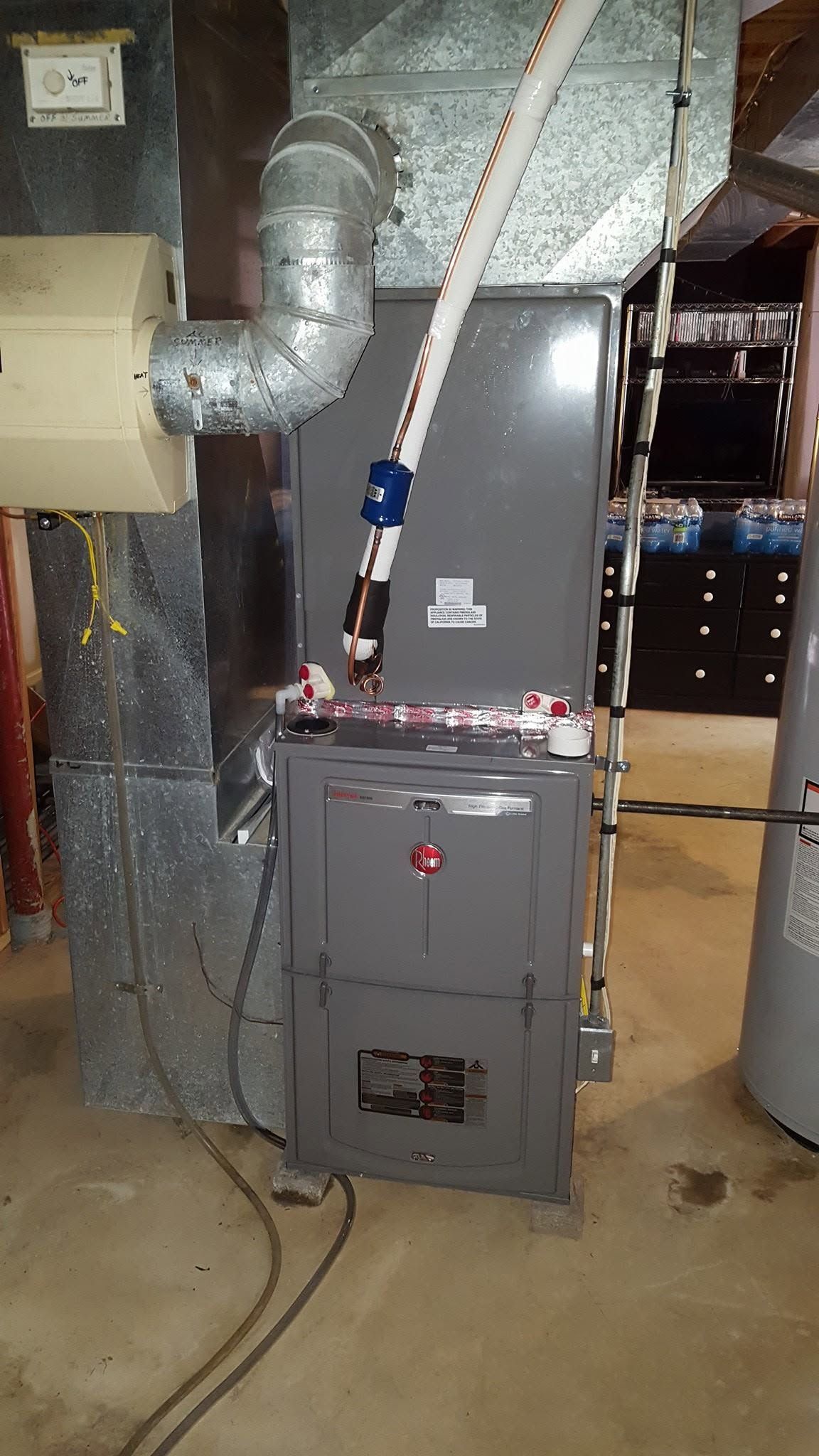 Basement HVAC furnace with silver ducts and a gray unit in a utility room