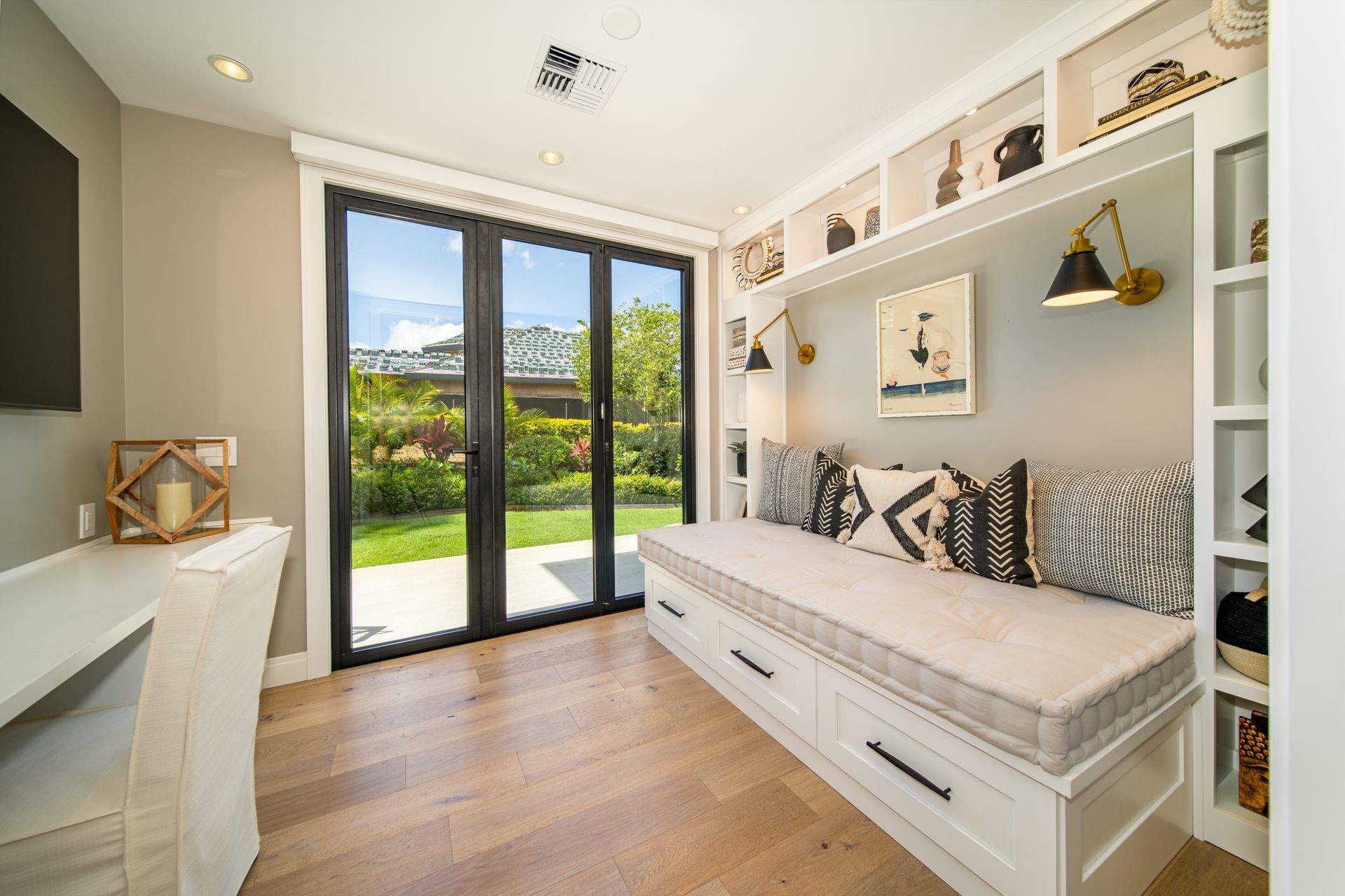 A living room with a couch , desk , and sliding glass doors.
