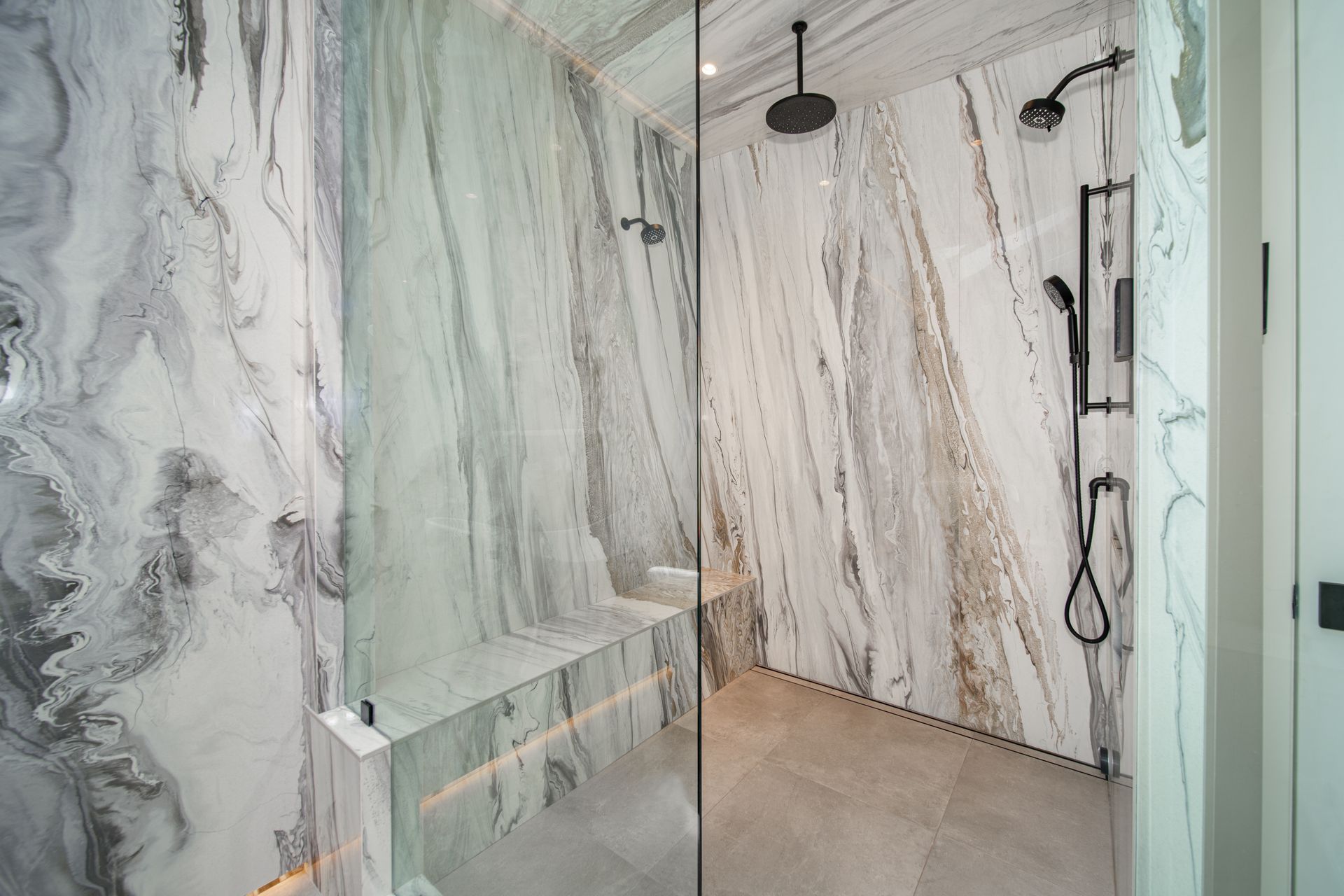A bathroom with a walk in shower and marble walls.