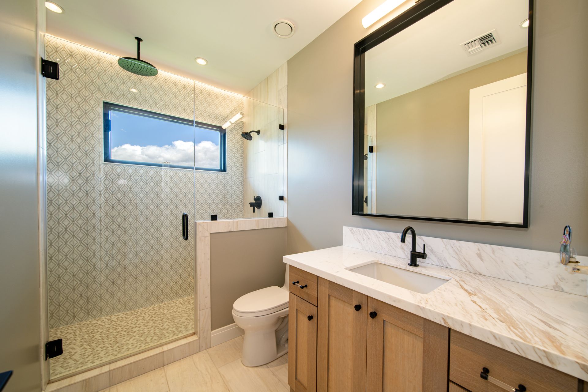 A bathroom with a toilet , sink , mirror and walk in shower.