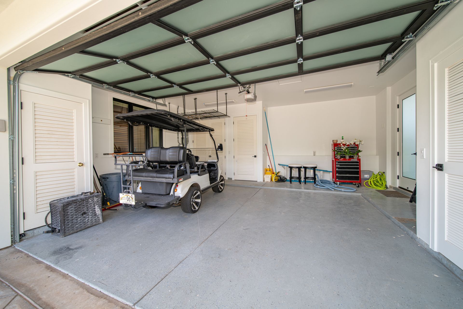 A golf cart is parked in a garage with its doors open.
