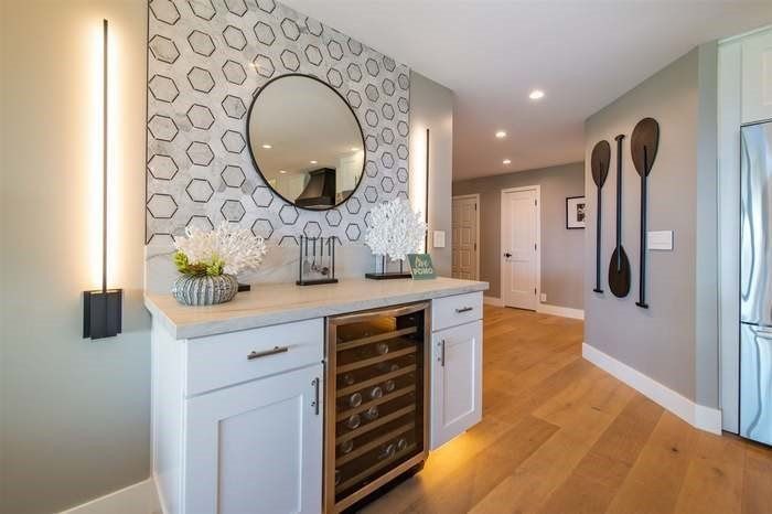 A kitchen with a wine cooler and a mirror on the wall.