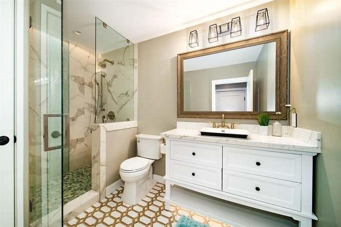 A bathroom with a toilet , sink , mirror and walk in shower.