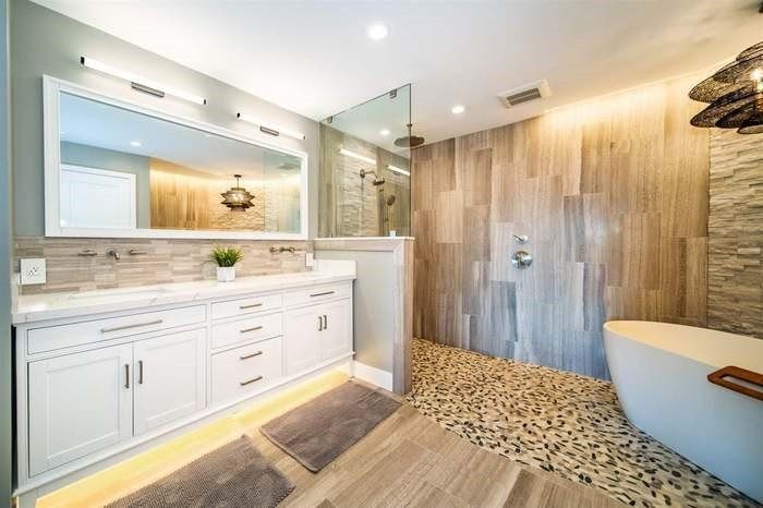 A bathroom with two sinks , a tub , and a walk in shower.